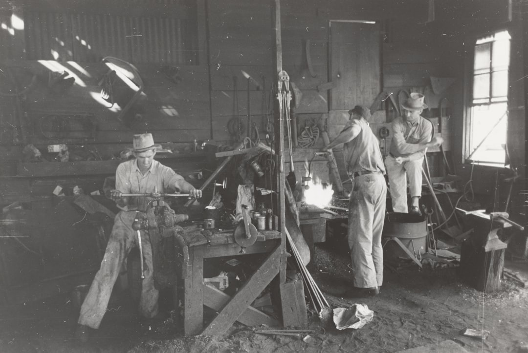 Three blacksmiths work together in a rustic metal shop.